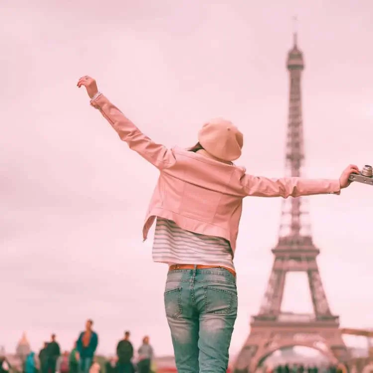 A happy traveler in France enjoys her stay in Paris, free from UTI symptoms because she knows what to do if you get a uti while traveling