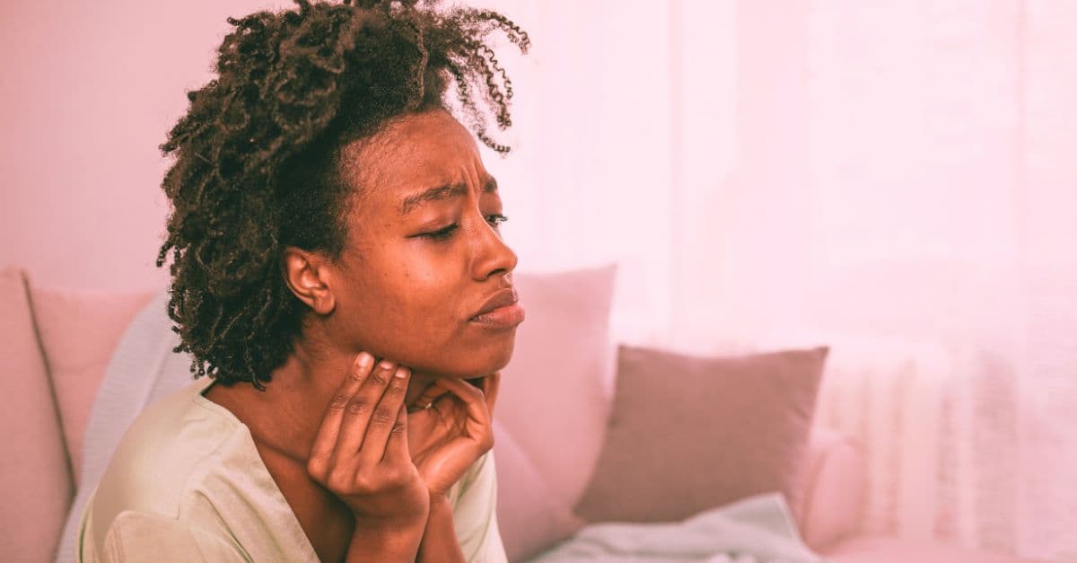 A young black woman experiences symptoms of sore throat on holiday