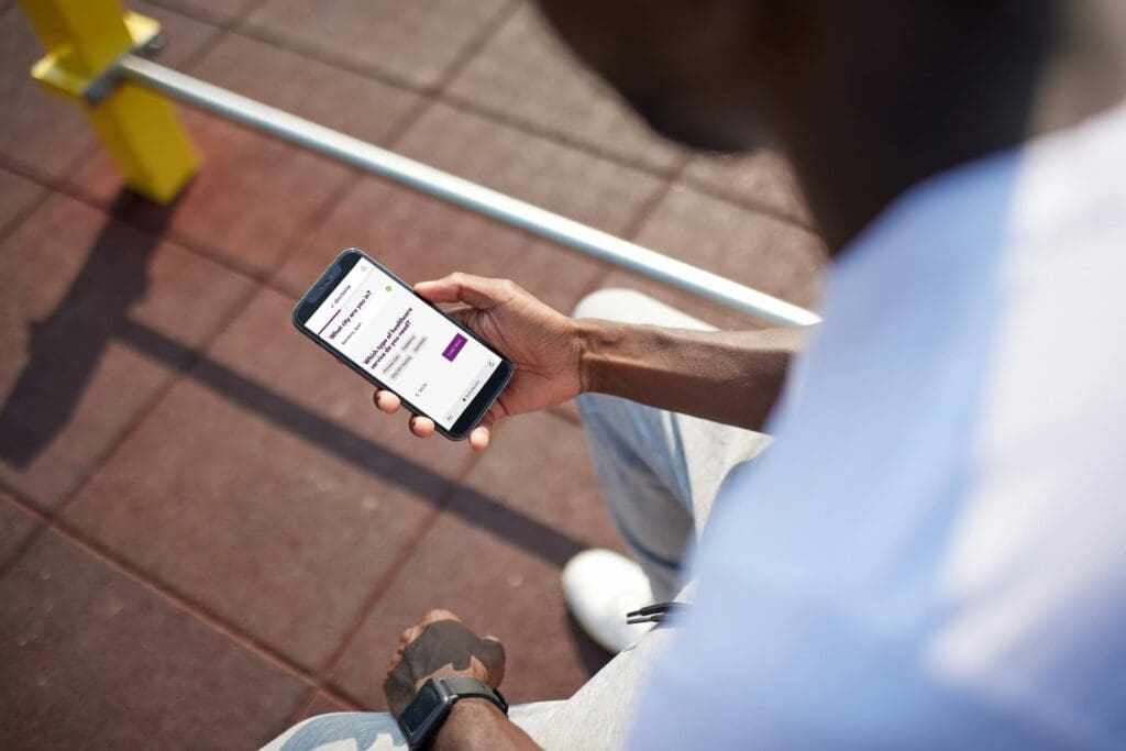 A man wearing a white shirt holds a smartphone to book an online consultation through Doctorsa to find a UTI doctor in Lisbon, highlighting the convenience of accessing medical care remotely.